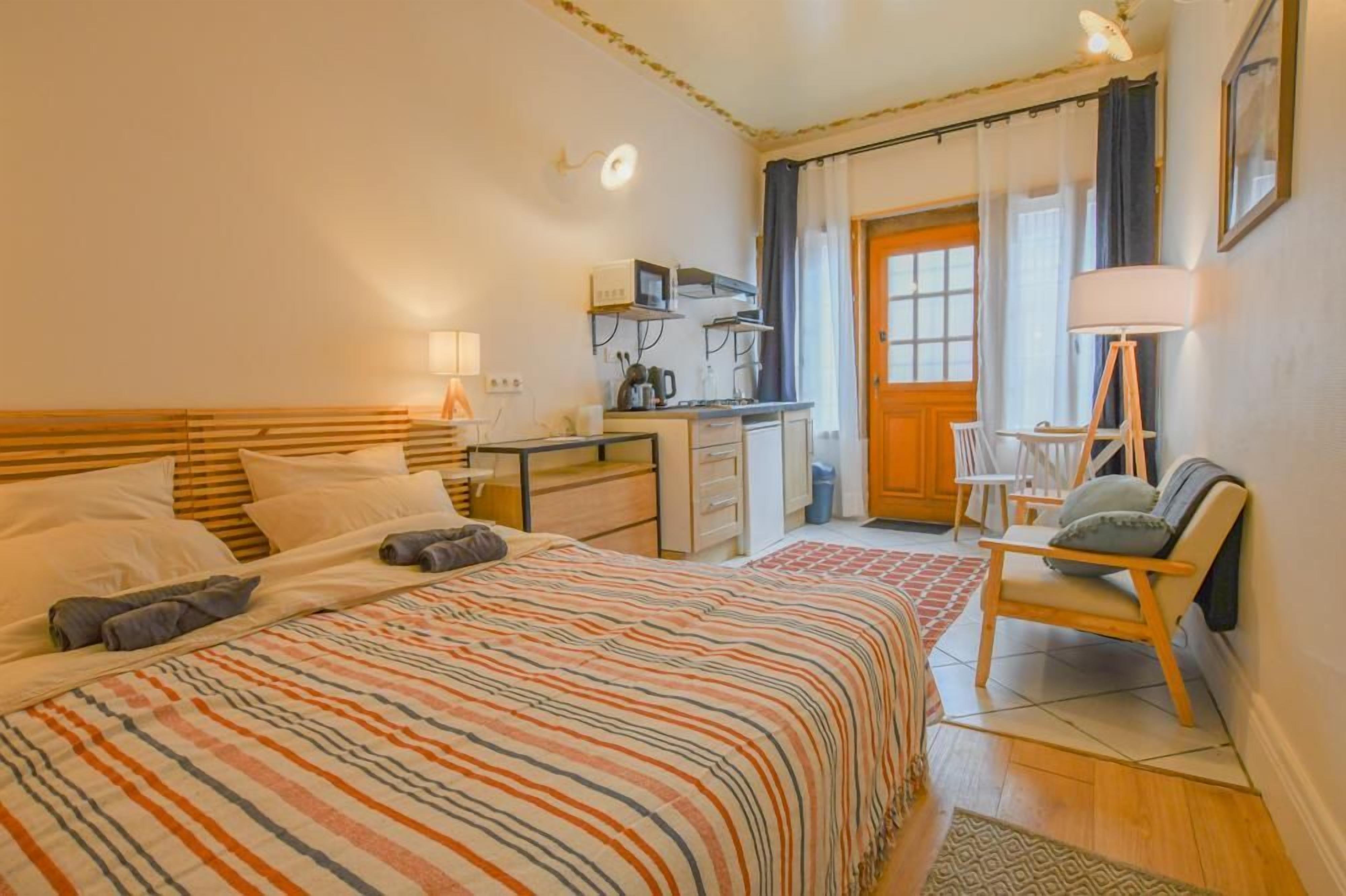 Een hotelkamer met een bed, een bureau, een stoel, een lamp en een deur naar een balkon.