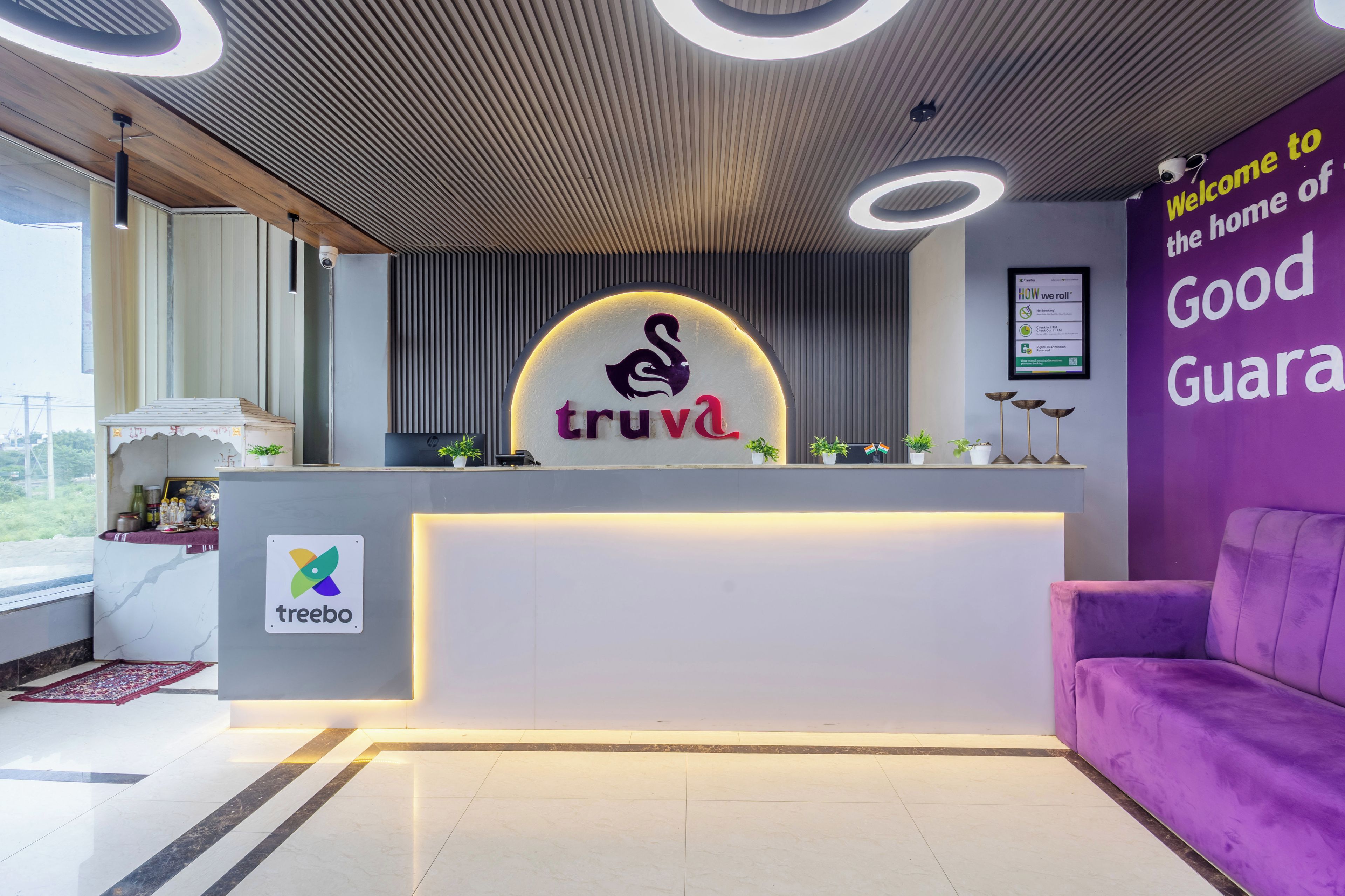 Una recepción con el logotipo 'truva', un cartel de 'treebo' y un sofá morado.