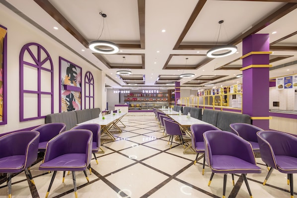 Un restaurante con decoración morada y dorada, con cabinas y mesas, y un cartel de menú al fondo.