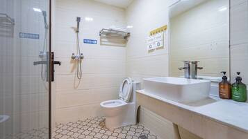A bathroom with a toilet, a shower, and a sink.
