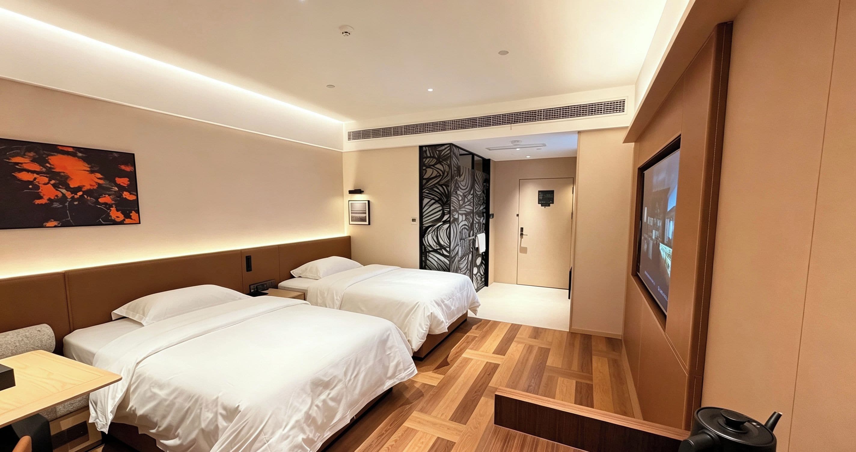Ein Hotelzimmer mit zwei Betten, einem Schreibtisch, einem an der Wand befestigten Fernseher und einer Tür zu einem weiteren Raum.