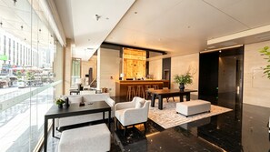 Eine moderne Lobby mit einer Rezeption, einer Sitzecke und Blick auf die Straße.