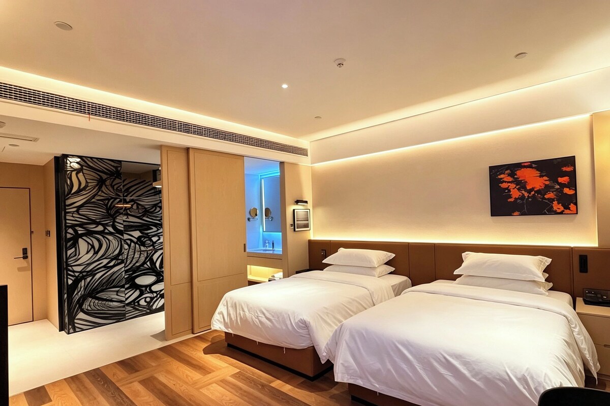 Ein Hotelzimmer mit zwei Betten, einem großen Spiegel, einem Wandbild und Holzboden.