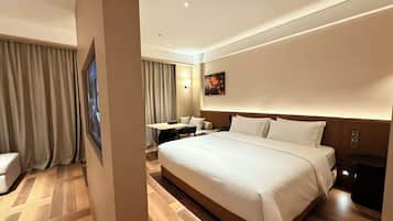 A hotel room with a large bed, a desk, and a chair.