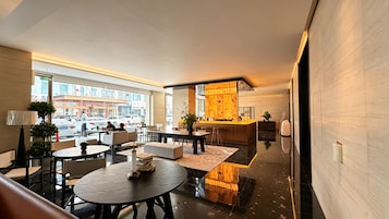 Un moderno vestíbulo de hotel con zona de bar, arreglos de asientos y vista a la calle.