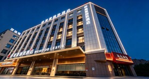 Un hotel con fachada moderna, varios pisos y señalización iluminada.