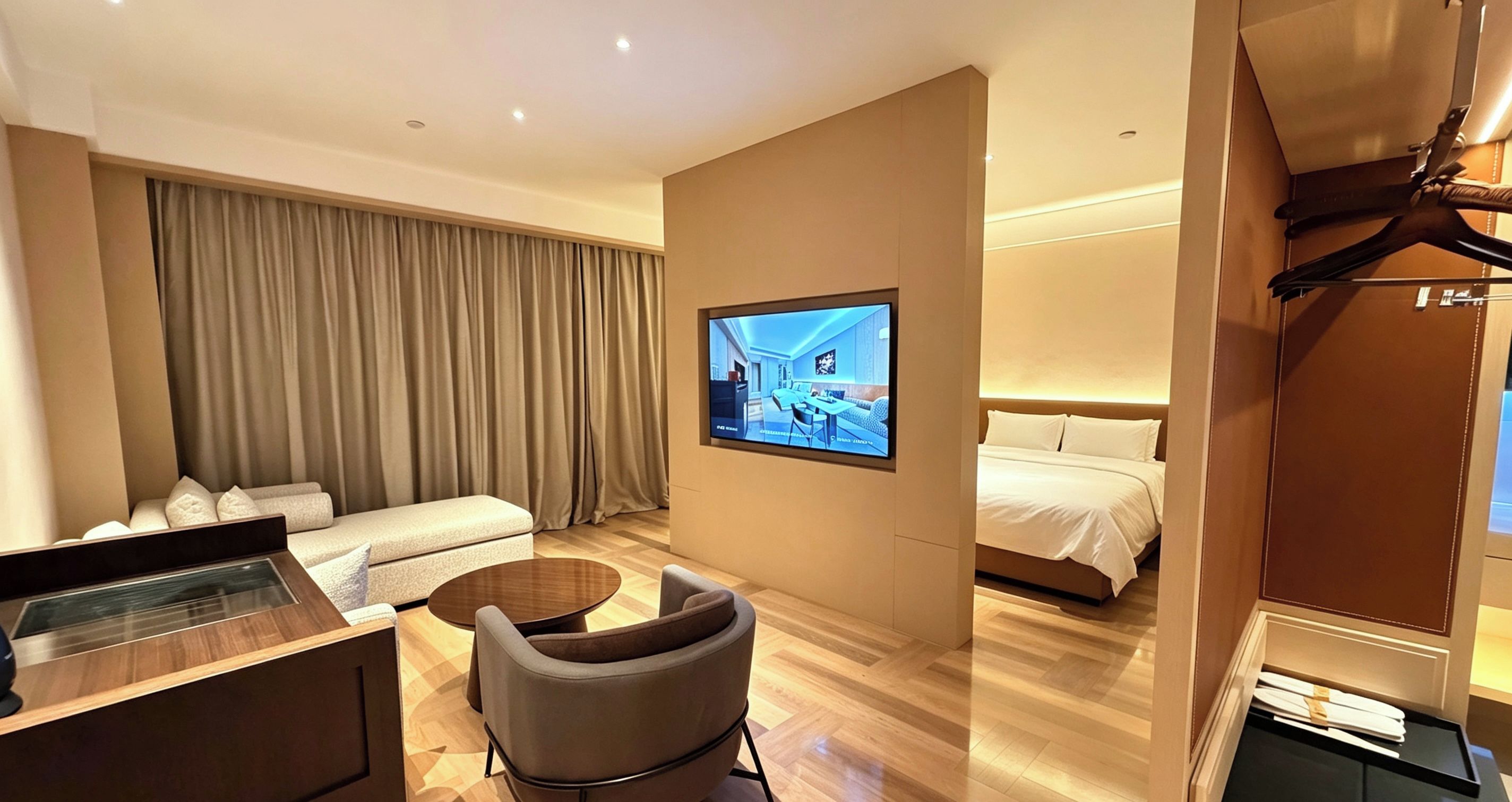 Ein Hotelzimmer mit einem Bett, einem Schreibtisch, einem Sessel, einem Fernseher und einem großen Fenster mit Vorhängen.
