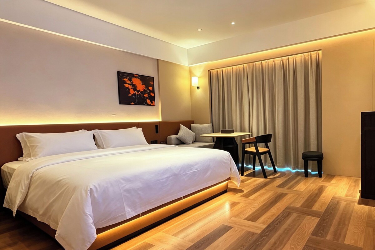 Ein Hotelzimmer mit Bett, Schreibtisch, Stuhl, Fernseher und Vorhang.
