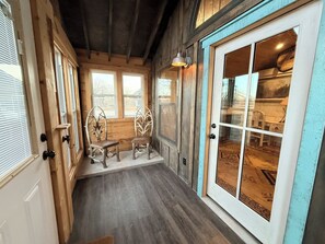 Ein Zimmer mit Holzwänden, einem großen Fenster, einer Glastür und einer Bank.