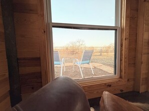 Ein Zimmer mit großem Fenster, Holzwänden und zwei blauen Stühlen davor.
