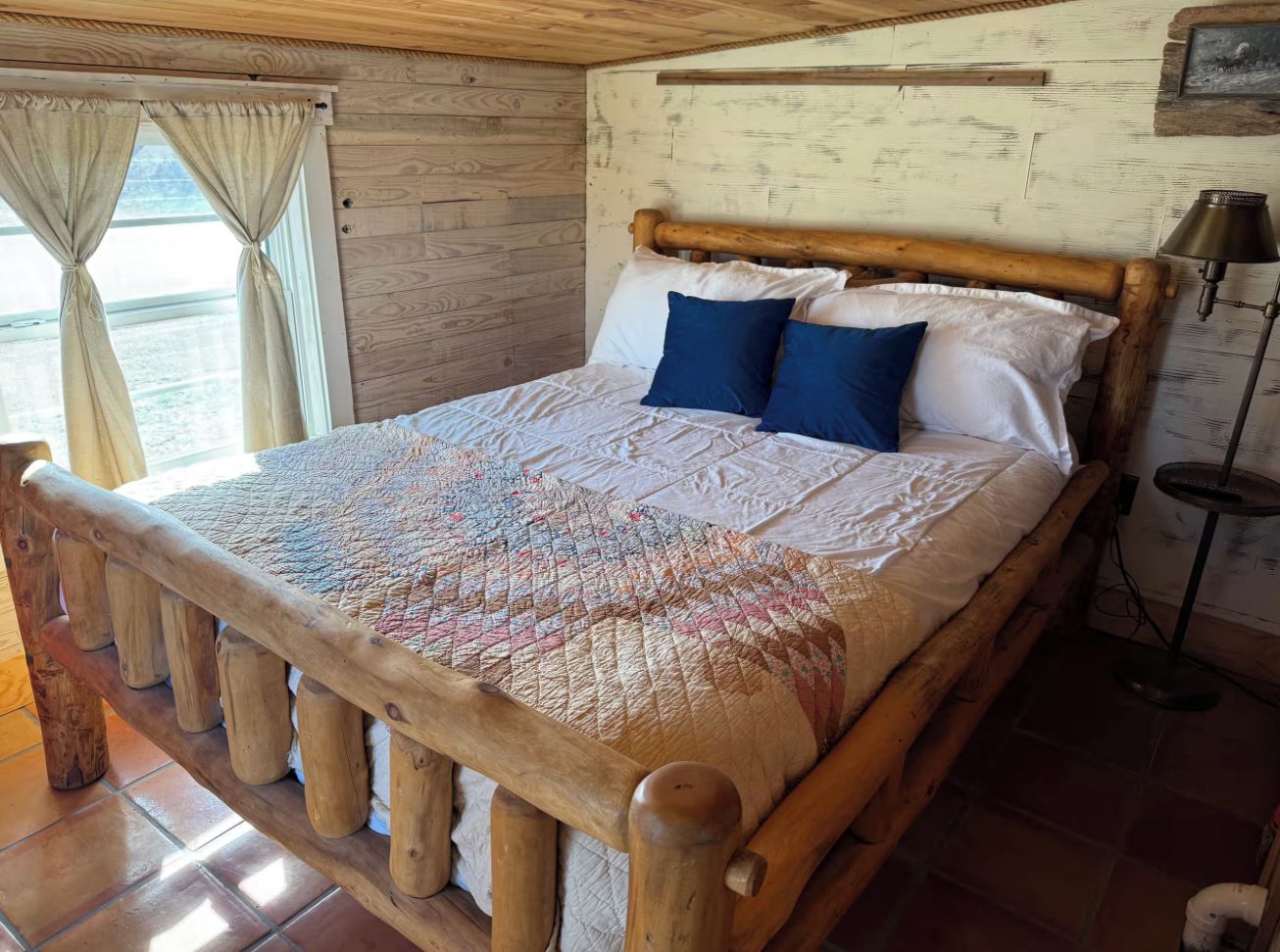 Uma cama de madeira com colcha, travesseiros e cabeceira.