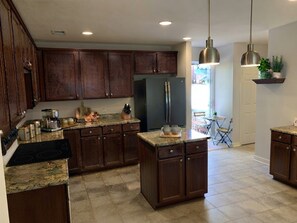 Une cuisine moderne avec des meubles de couleur bois foncé, un réfrigérateur en acier inoxydable et un plan de travail en granit.