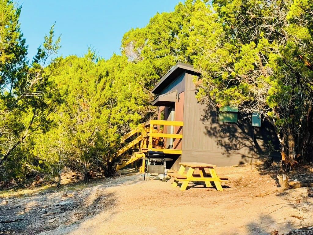 A wooden structure with a staircase leading to a door, surrounded by trees.