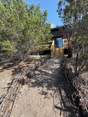 Una cabaña rústica con terraza de madera, rodeada de densos pinos.
