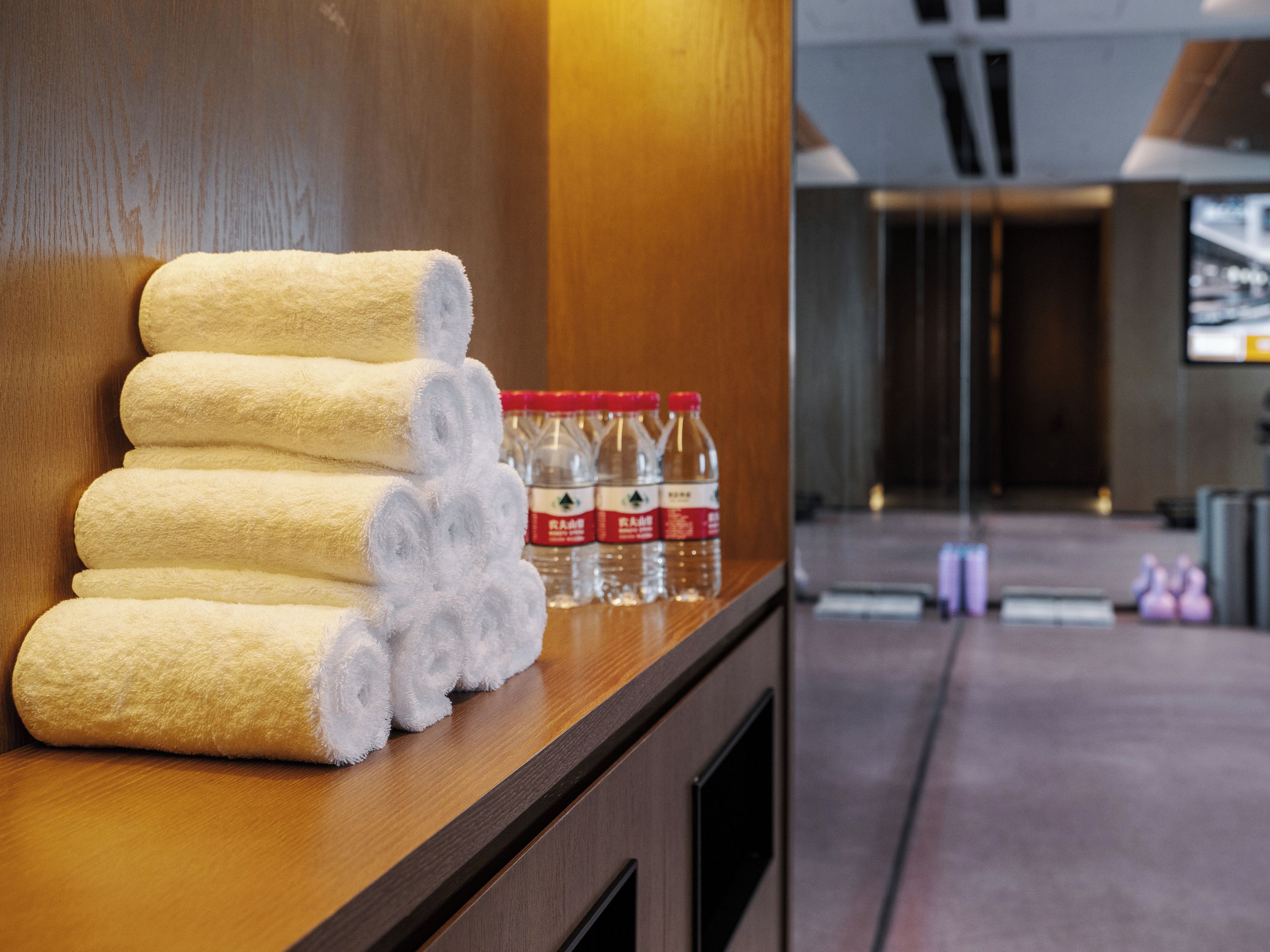 Zona de recepción de hotel con un mostrador de madera que exhibe toallas enrolladas y botellas de agua.