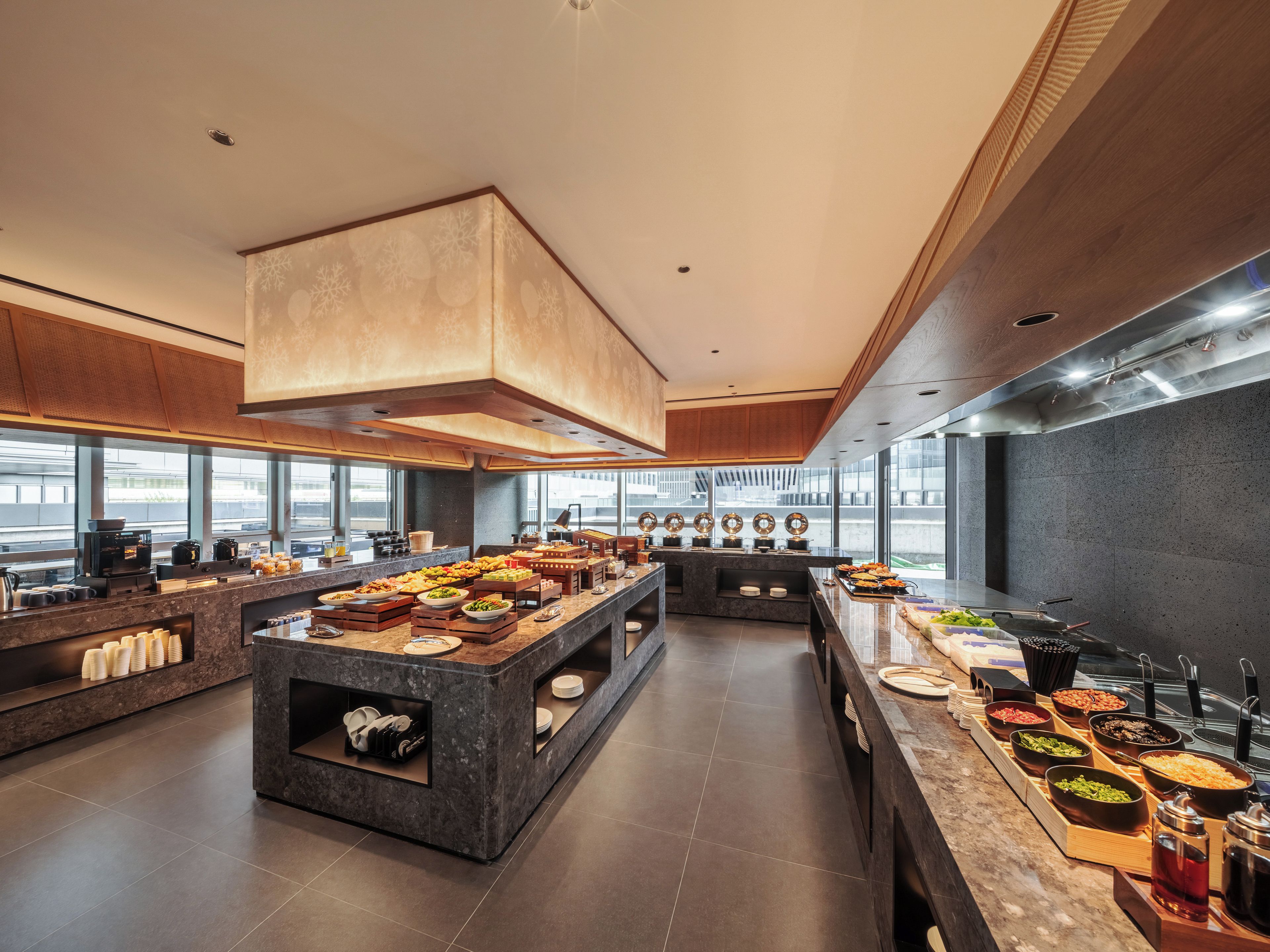 Cocina moderna con una isla central, diferentes estaciones de comida y un amplio ventanal con vistas a la ciudad.
