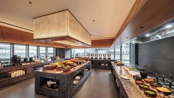 Cocina moderna con una isla central, diferentes estaciones de comida y un amplio ventanal con vistas a la ciudad.