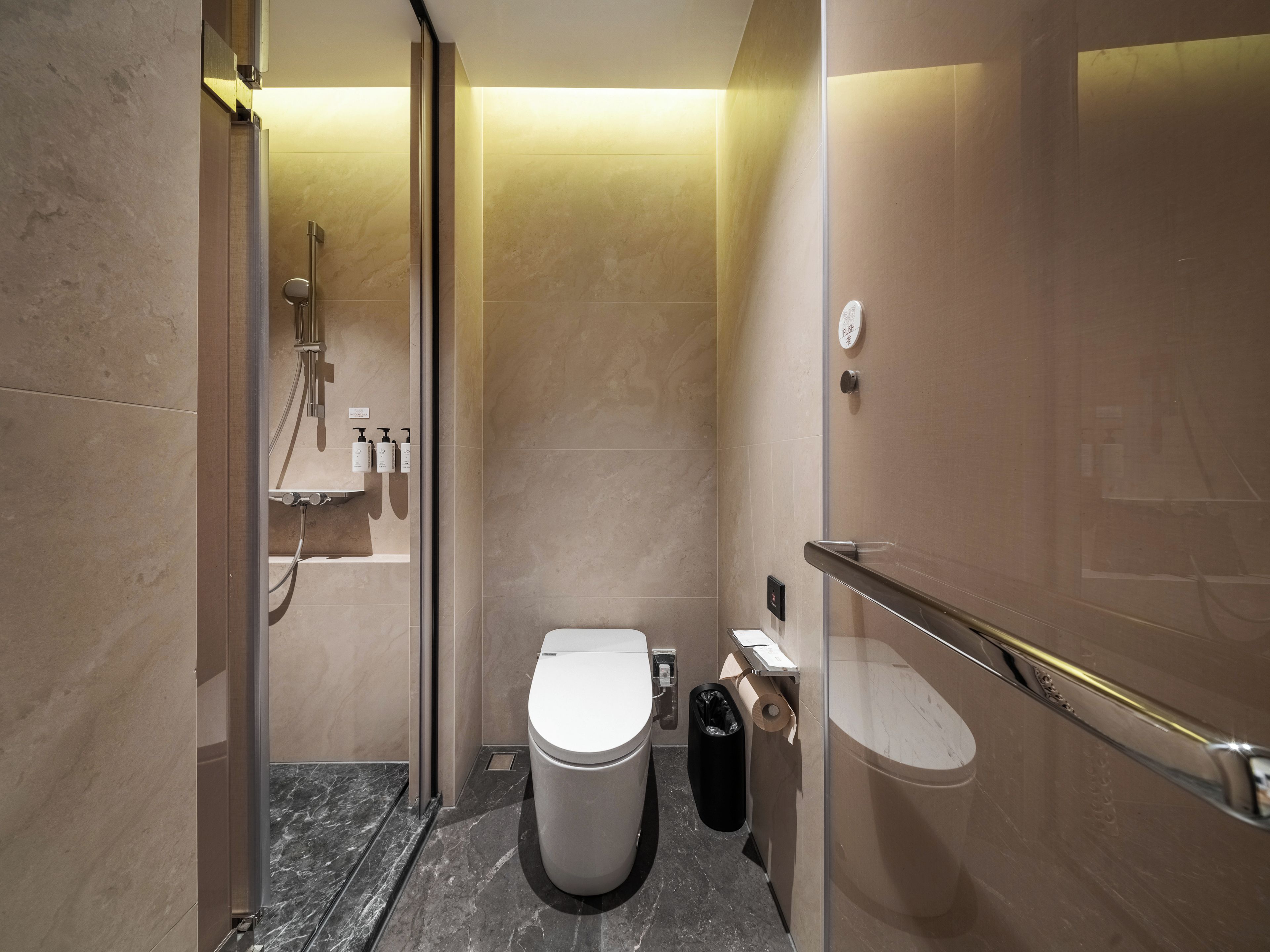 A modern bathroom with a toilet, shower, and hand dryer.