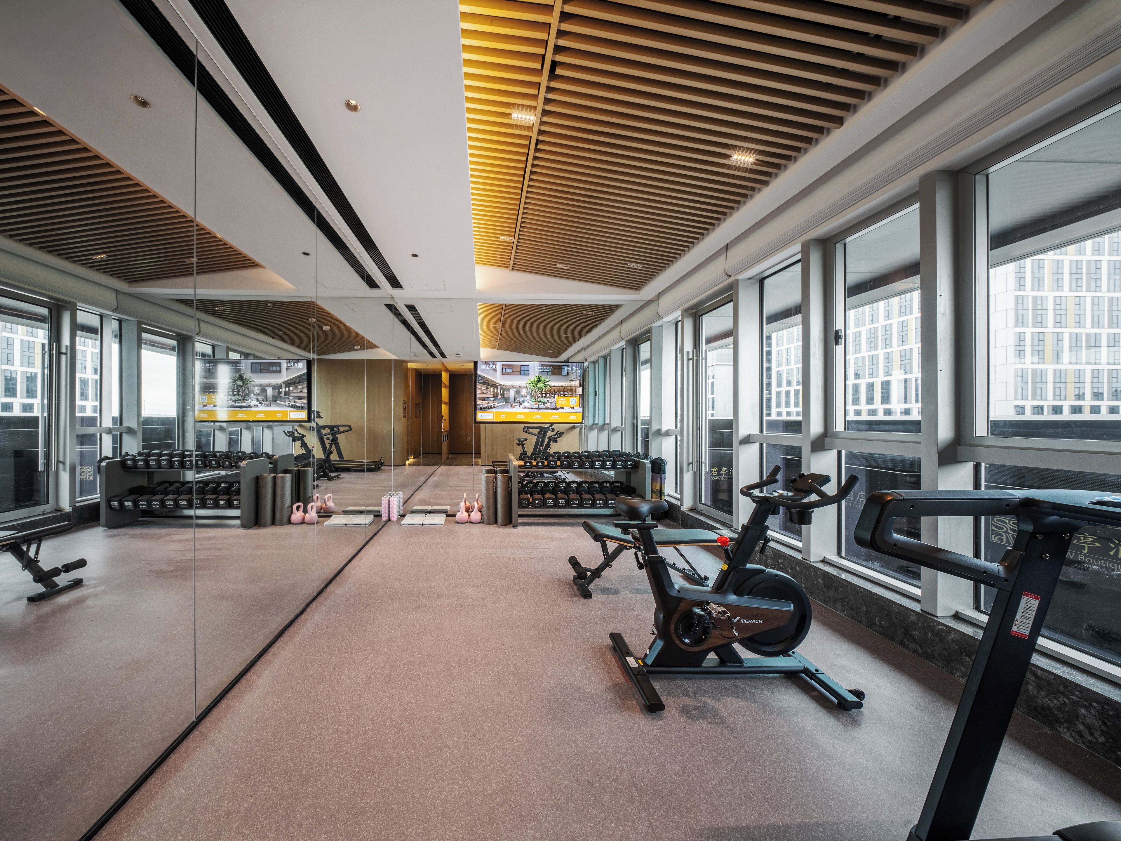 Un gimnasio con equipamiento de ejercicio, amplias ventanas y un diseño de interiores moderno.