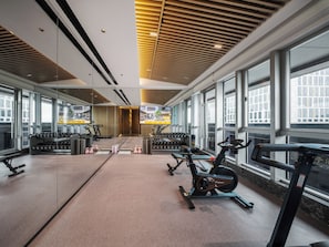 Een sportschool met trainingsapparatuur, grote ramen en een modern interieur.