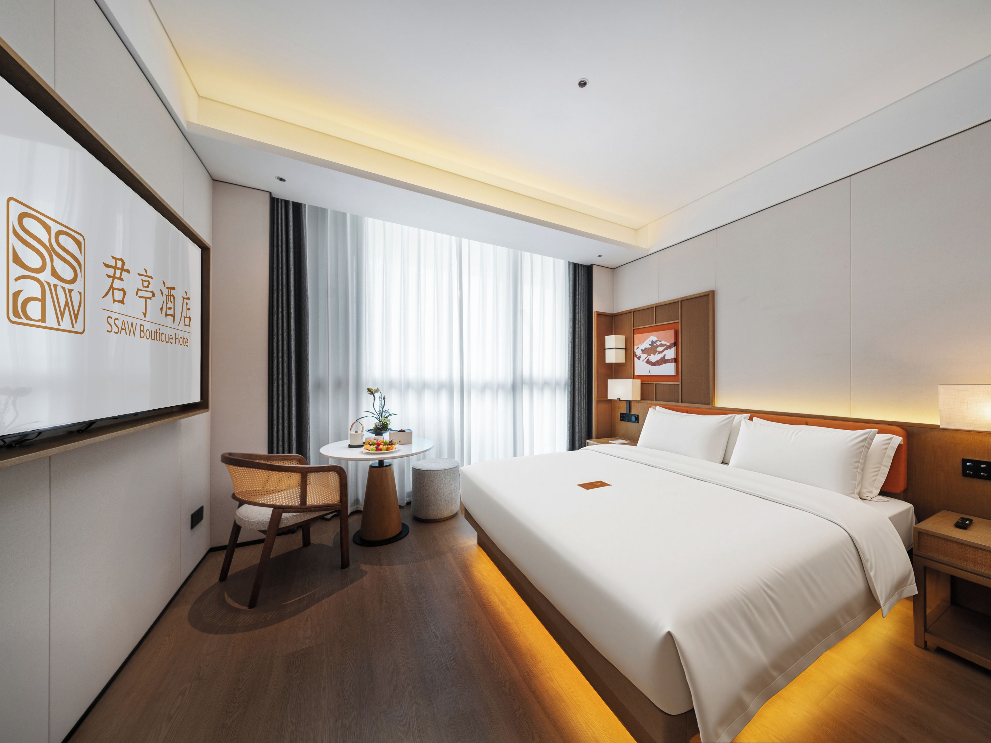 Una habitación de hotel con cama, mesita de noche, lámpara, silla y una pequeña mesa con una planta.