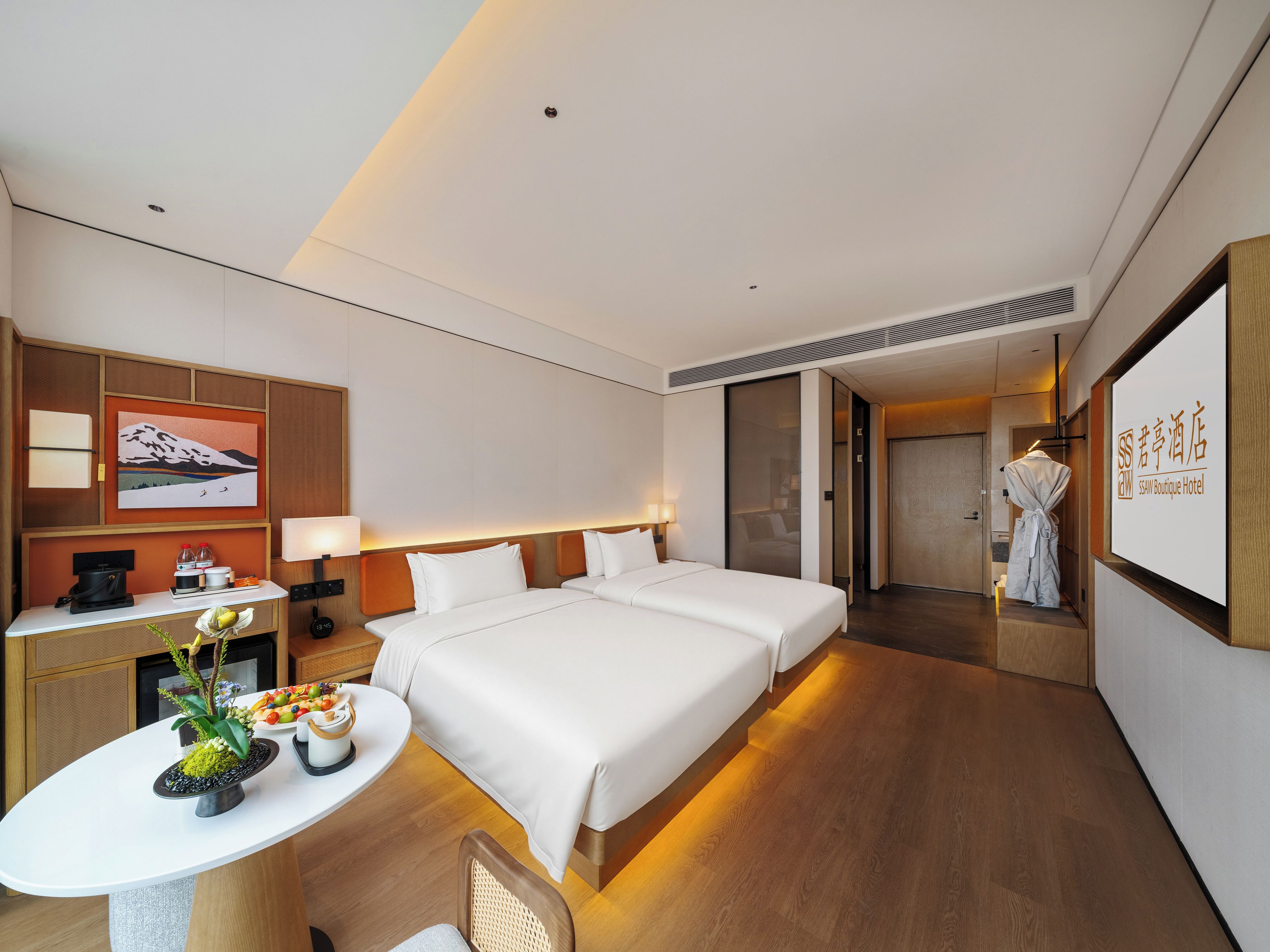 Habitación de hotel con cama, mesita de noche, lámpara y televisor montado en la pared.