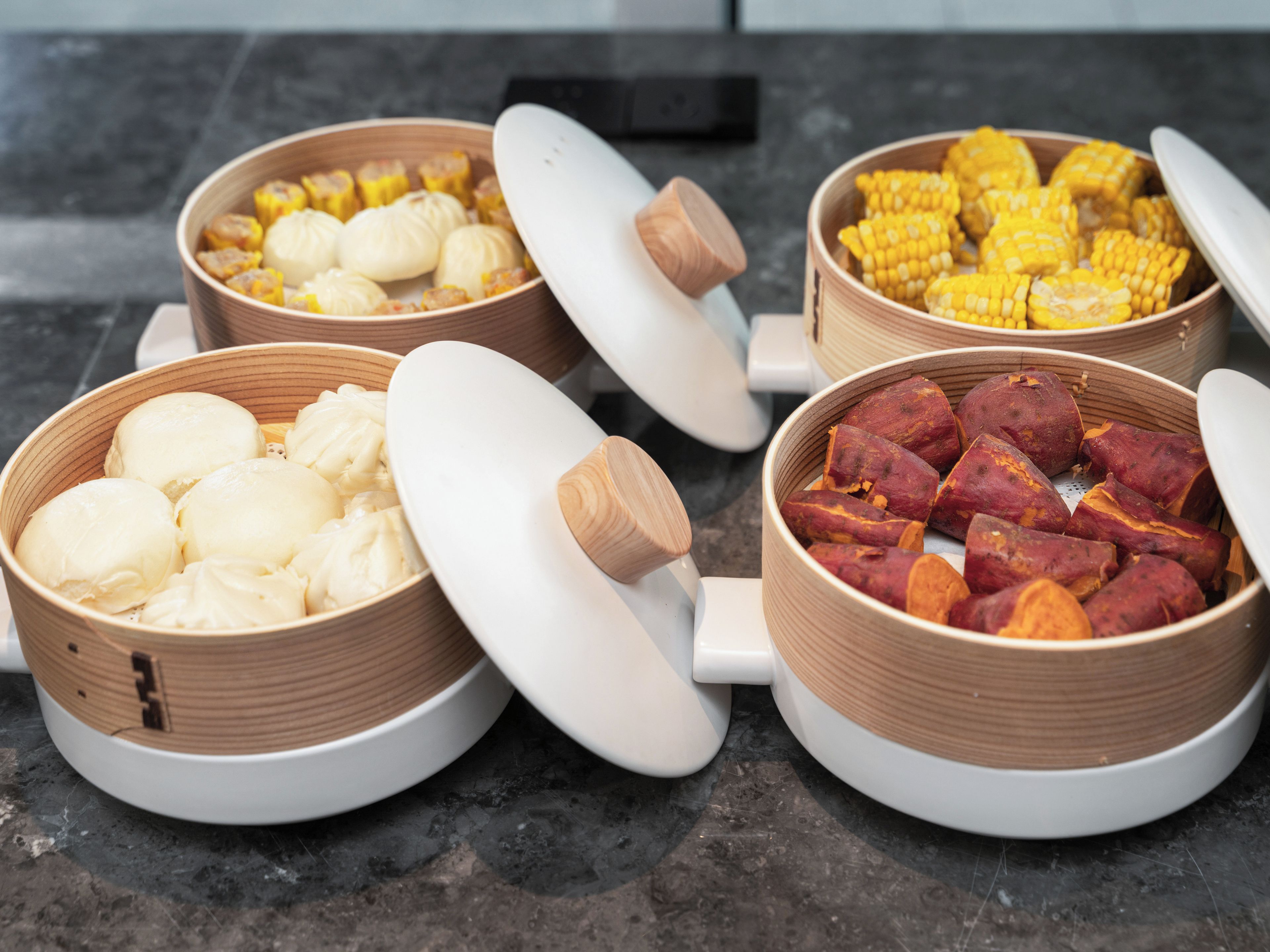 Quatre récipients en céramique, dotés de couvercles, sont posés sur un plan de travail de cuisine.