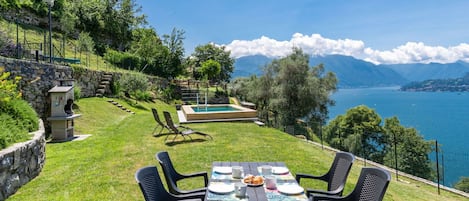 A dining area with a table set for four, overlooking a lake with mountains in the distance.