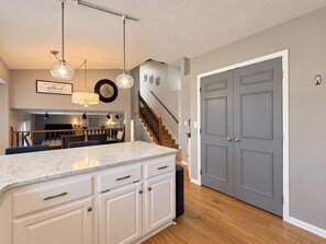A kitchen with a marble countertop, white cabinetry, and a wooden staircase. - Immaculate Modern Oasis - Huge Backyard (Mead)