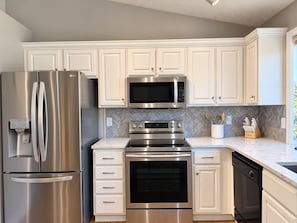A modern kitchen with stainless steel appliances, white cabinetry, and a herringbone tile backsplash. - Immaculate Modern Oasis - Huge Backyard (Mead)