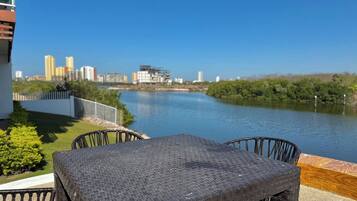 Una terraza con mesa y sillas que da a un río, con edificios al fondo.