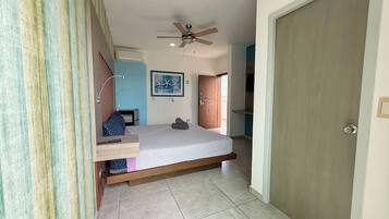 A bedroom with a bed, a ceiling fan, a door, and a window.