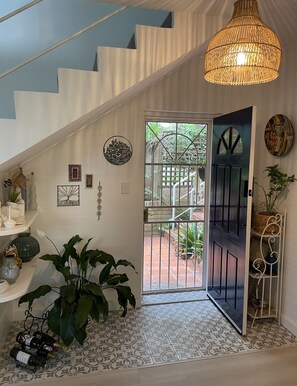 A staircase with a hanging light fixture, a door leading to an outdoor area, and decorative wall art. - Family Townhouse Randwick (Randwick)