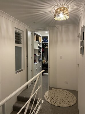 En hall med en trappa, en garderob med upphängda kläder och en dekorativ lampa.