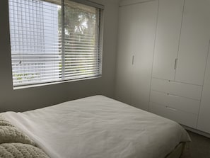 A bedroom with a bed, a window with blinds, and a wardrobe. - Family Townhouse Randwick (Randwick)