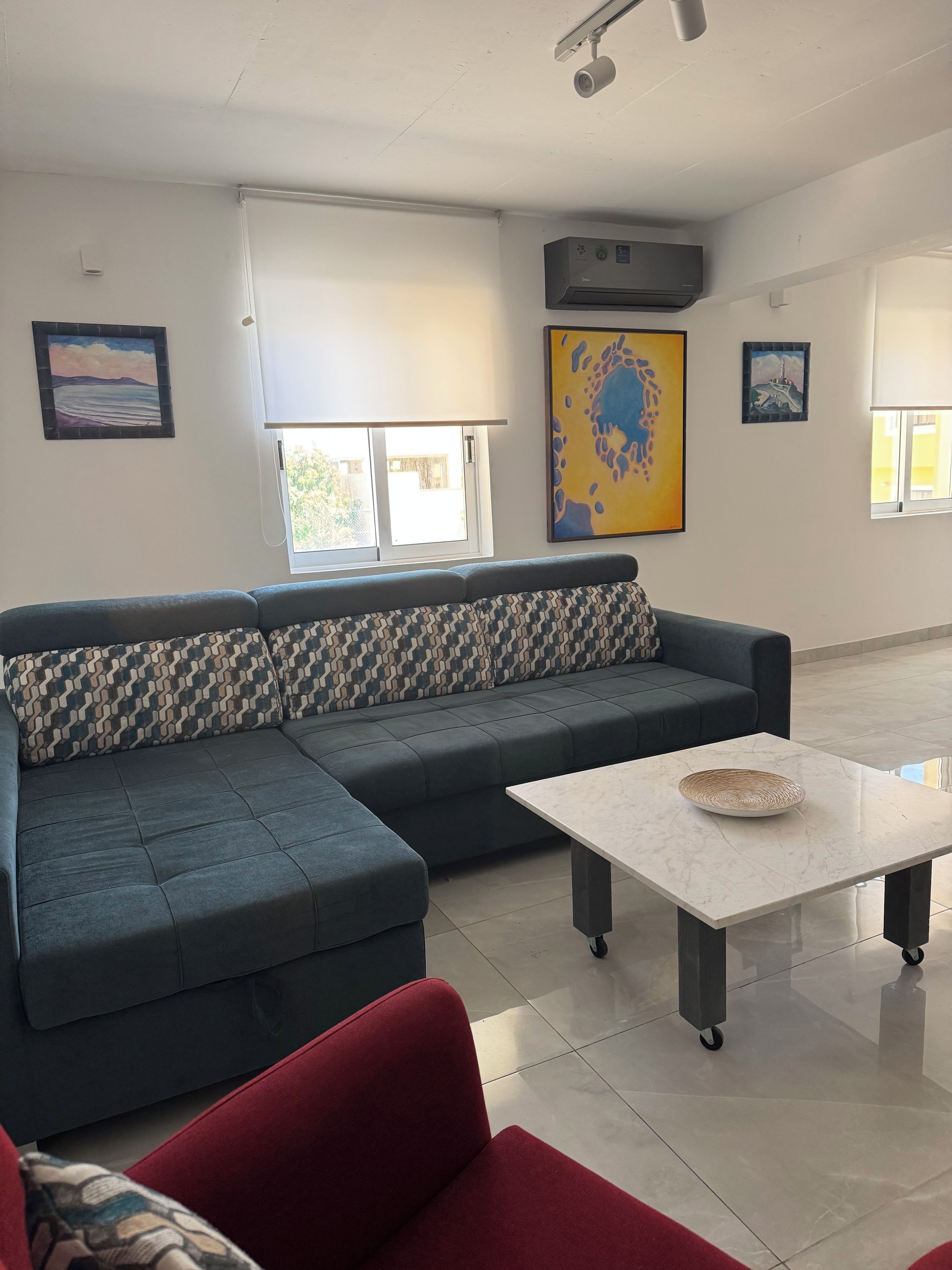 A modern living room with a sectional sofa, a red armchair, a coffee table, and artwork on the walls.