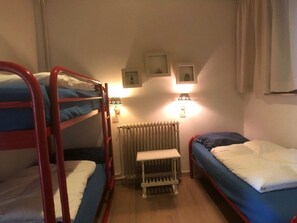 A dormitory room with bunk beds, a radiator, a bedside table, and wall-mounted light fixtures. - Zouterik Ground Floor (Cadzand-Bad)