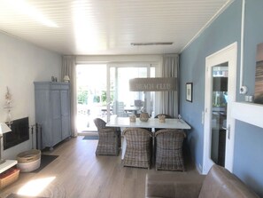 A dining area with wicker chairs, a white table, and a sign that reads 'BEACH CLUB'. - Zouterik Ground Floor (Cadzand-Bad)