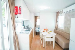 Cuina compacta amb rentamillera, fogons i zona de menjador amb taula i cadires.