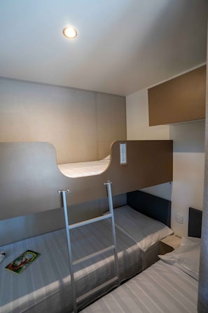 Una camera con un letto a castello, una scala, un tavolino e una rivista sul letto inferiore.