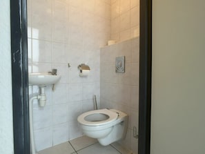 A small, clean bathroom with a toilet, sink, and toilet paper holder. - Wijk de Brabander 58 (Cadzand-Bad)