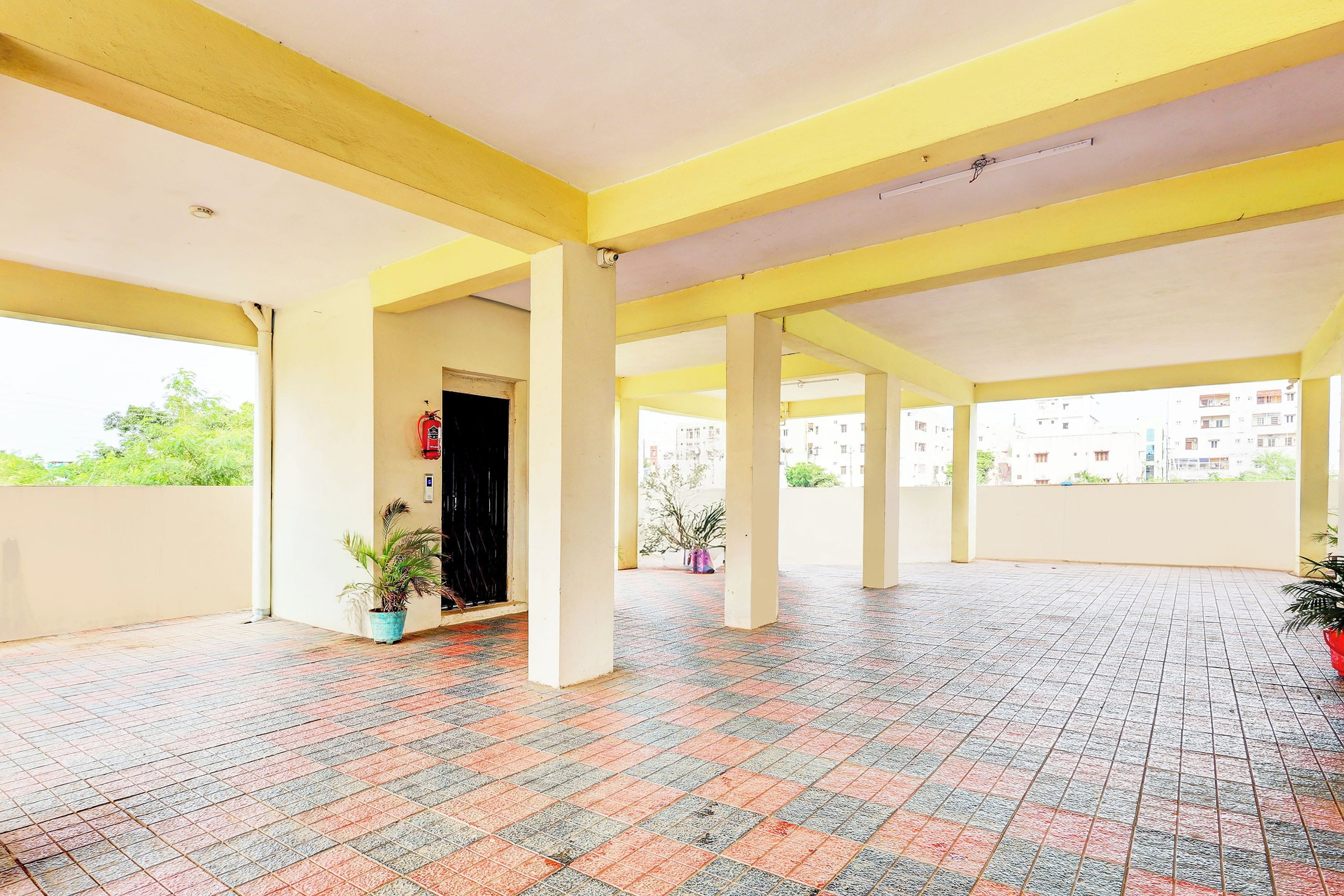 A covered outdoor area with tiled flooring and yellow structural beams.