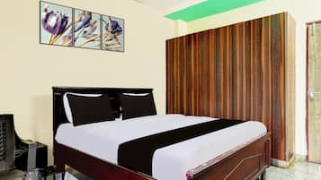 A hotel room with a bed, a wooden wardrobe, a green ceiling, and a wall-mounted artwork.