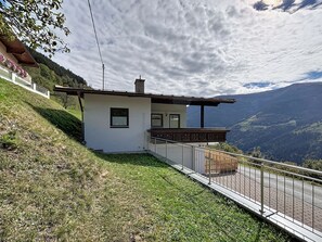 Un chalet moderne doté d’un balcon offrant une vue sur un paysage montagneux.