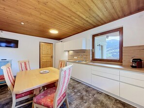 Une cuisine compacte avec un plafond en bois, une table à manger avec des chaises, une fenêtre offrant une belle vue et un four encastré.