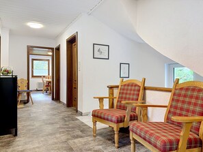 Un couloir avec des chaises en bois, un radiateur et des tableaux encadrés accrochés au mur.