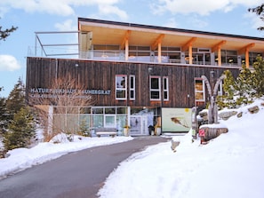 Ein modernes Gebäude mit Holzfassade und großen Fenstern, mit dem Aufdruck 'NATURARKHAUS KAUNERGRAT CAFE-RESTAURANT'.