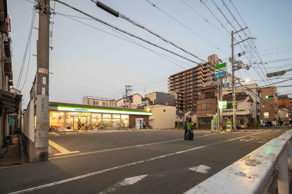 A street view with a FamilyMart store, a multi-story building, and a pedestrian crossing.