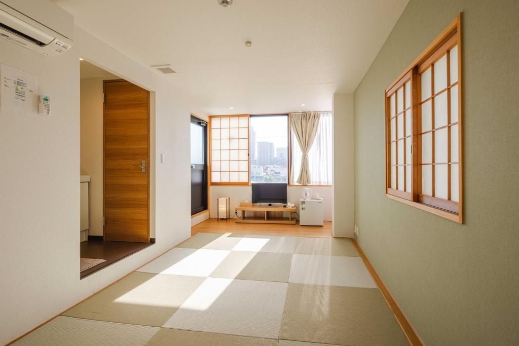 A room with tatami flooring, a sliding door, a television, and a view of the city through large windows.