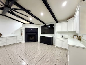 A spacious kitchen with white cabinetry, a black fireplace, and a tiled floor. - Spacious 4BR Retreat on 2 Acres •Sleeps 9 (San Benito)